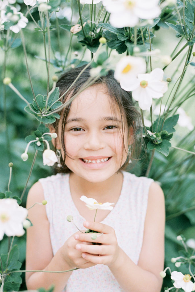 A smiling girl among white flowers brown eyes