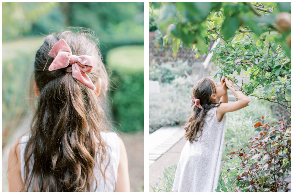 Pink hair bow in dark hair and a little girl smelling tree blossoms at Mellon Park's Phipp's Conservatory Walled Garden