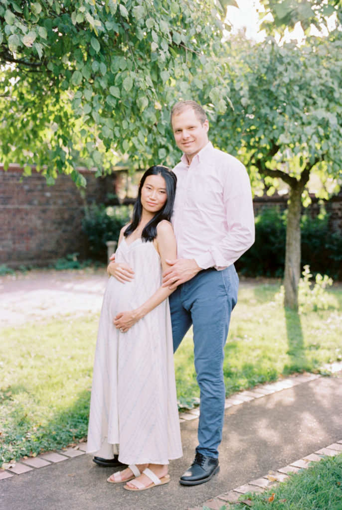 Expectant parents in a walled garden with dappled sunlight film photography Mellon Park Phipp's Conservatory Walled Garden | Pittsburgh Family Photography by Anna Laero Photography