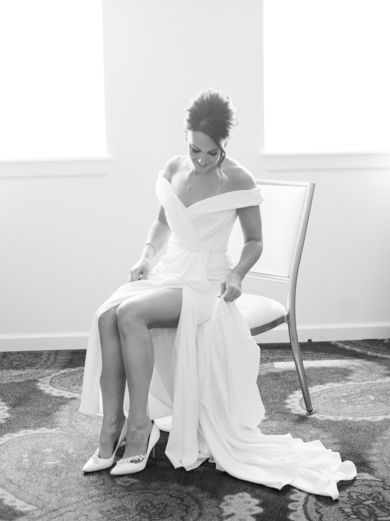The bride excitedly slides her foot into her Manolo Blahnik shoes in this black and white Pittsburgh wedding photograph.