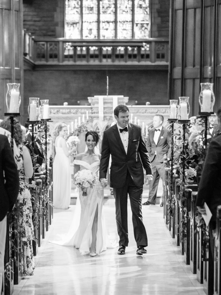 The bride and groom walk hand-in-hand down the aisle radiating joy as they are now married.