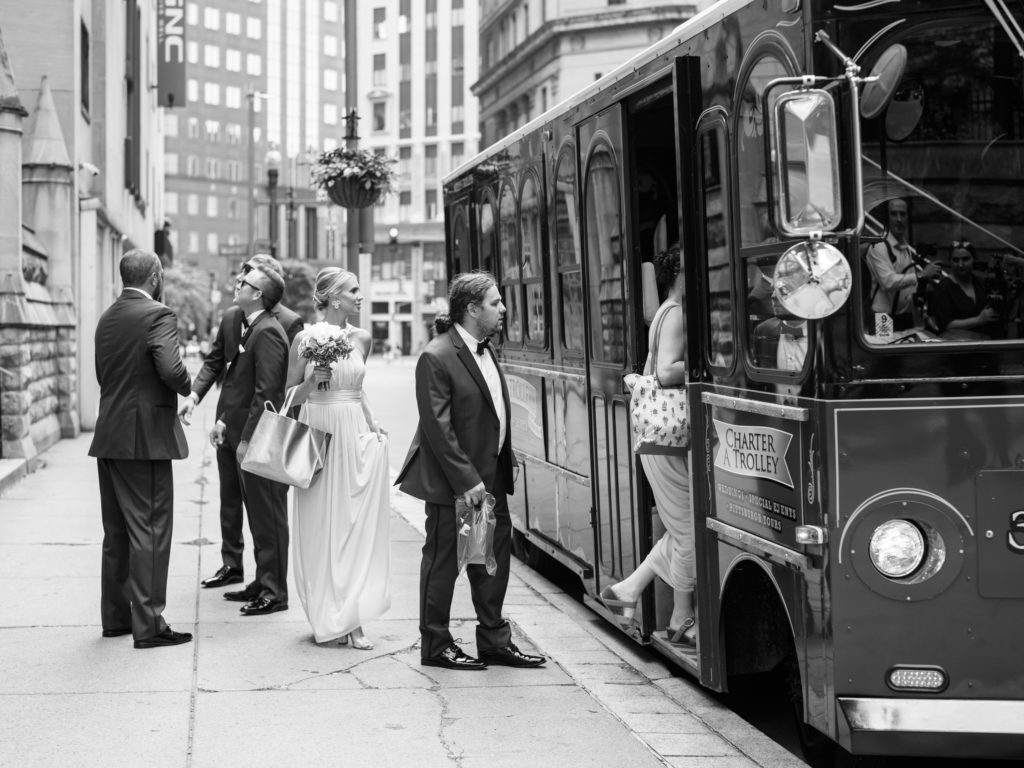 In a black and white photograph the wedding party boards a trolley in Pittsburgh, PA.
